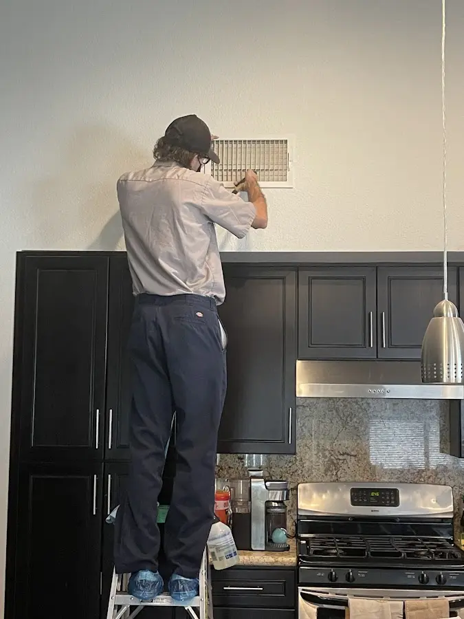 Technician inspecting an air vent during HVAC service in Owego